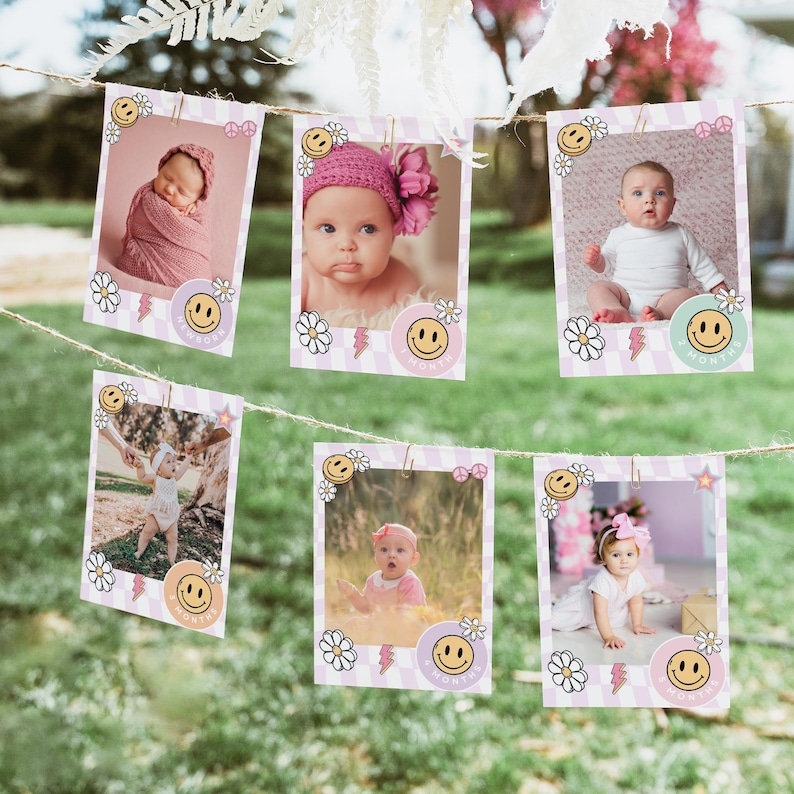 May include: A string of six pink and white photo cards with smiling faces and flowers. Each card has a photo of a baby in different poses. The cards are strung together with twine.
