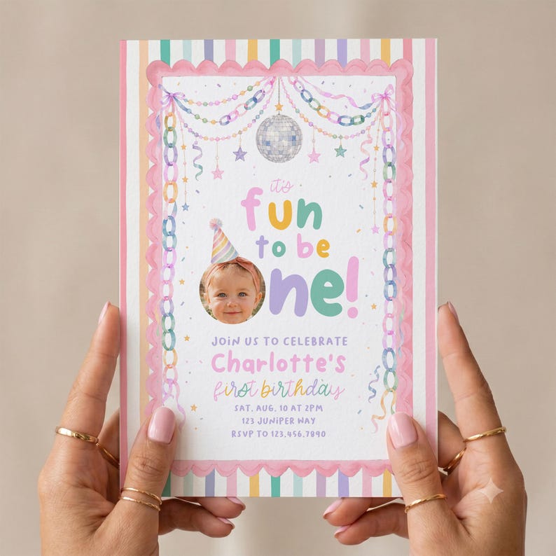 K&ouml;nnte beinhalten: Eine rechteckige Geburtstagseinladungskarte mit pastellfarbenem Streifenrand, einer Discokugel und bunten Papierketten. Der Text lautet: It's fun to be one! Join us to celebrate Charlotte's first birthday, Sat, Aug, 10 at 2pm, 123 Juniper Way, RSVP to 123.456.7890.