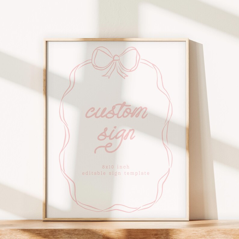 May include: A framed sign with a light pink bow and ribbon design. The sign reads "custom sign" in cursive, with "8x10 inch editable sign template" below. The frame is a light wood color.