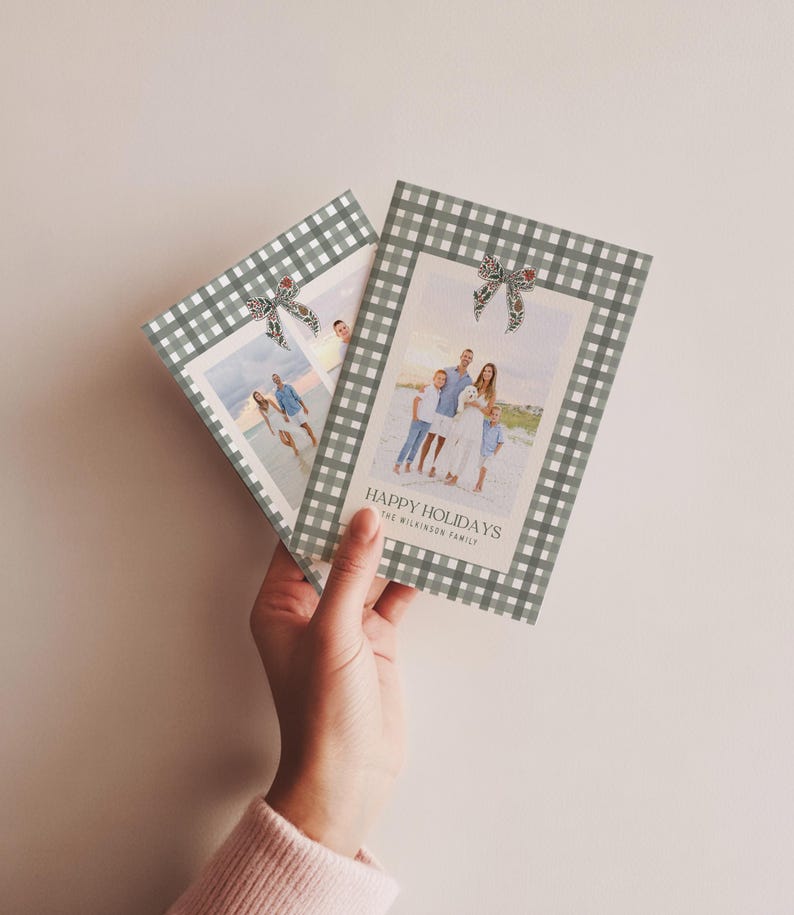 May include: Two holiday greeting cards with family photos. The cards have a gray and white gingham border and a decorative bow. The text "HAPPY HOLIDAYS" and family name are printed on the front of the card.