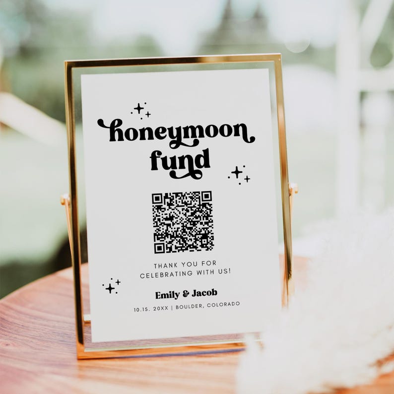 K&ouml;nnte beinhalten: Ein goldfarbener Rahmen mit einem wei&szlig;en Hintergrund und schwarzem Text, der "honeymoon fund" lautet. Unter dem Text ist ein QR-Code abgebildet, zusammen mit der Nachricht "Vielen Dank f&uuml;r die Feier mit uns! Emily & Jacob 10.15. 20XX | BOULDER, COLORADO".