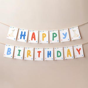 Puede incluir: Una guirnalda de cumplea&ntilde;os de dos filas con tarjetas rectangulares blancas colgadas de un cordel. Cada tarjeta muestra una letra colorida que forma HAPPY BIRTHDAY en azul, rojo, amarillo y verde, con estrellas y dibujos de ocas.