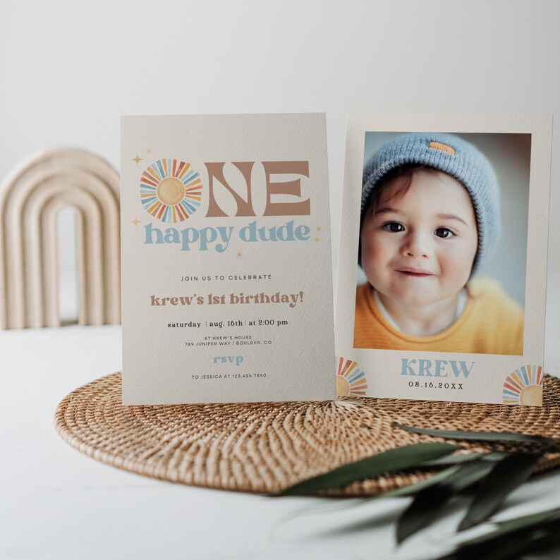 May include: A two-piece birthday invitation set. The left card reads "ONE happy dude" with a sun graphic. The right card features a photo of a baby and the name "Krew". The invitation includes event details.