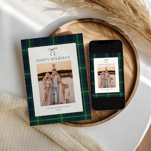 May include: A holiday card and a smartphone displaying the same image. The card and phone screen feature a family photo with the text "HAPPY HOLIDAYS" and a plaid border in navy blue, green, and white. The family photo is on a white background.