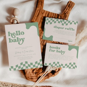 May include: A set of three rectangular paper cards with a light pink background, sage green wavy accents, and a checkered pattern. The cards feature the text hello baby, diaper raffle, and books for baby in a bold, rounded sage green font.