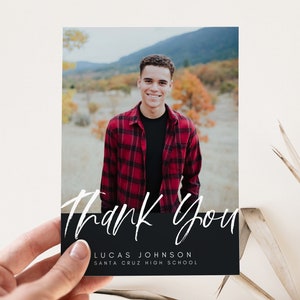 May include: A black and white thank you card with a photo of a person in a red and black plaid shirt. The text "Thank You" is written in white script on a black background. The text "Lucas Johnson" and "Santa Cruz High School" is written in white on the black background.