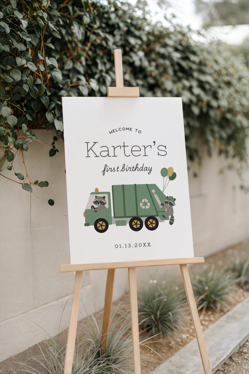 May include: A white sign on a wooden easel with the text "Welcome to Karter's first birthday." A green garbage truck illustration with raccoons and balloons is featured. The date 01.13.20XX is printed below the truck.