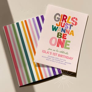 May include: A rectangular invitation card and a matching envelope featuring vertical stripes in purple, pink, green, orange, and teal. The card displays the text GIRLS JUST WANNA BE ONE, join us to celebrate ISLA'S 1ST BIRTHDAY, and event details.