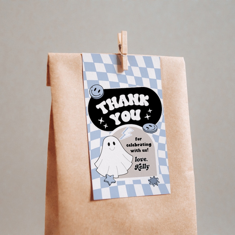 May include: A brown paper gift bag with a light blue and white checkered tag. The tag says "THANK YOU" in a black oval with smiley faces and stars. A ghost illustration and the text "for celebrating with us! love, Kelly" are also on the tag.