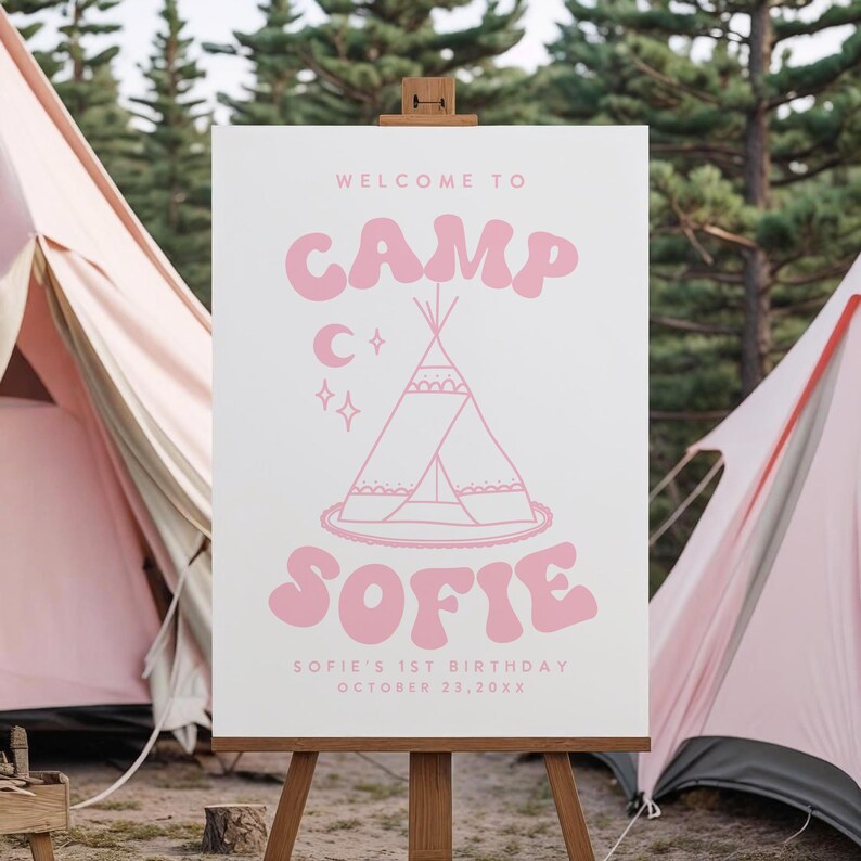 May include: A white sign on a wooden easel with pink text and illustrations. The sign reads "WELCOME TO CAMP SOFIE" with a teepee illustration, a crescent moon, and stars. The text "SOFIE'S 1ST BIRTHDAY OCTOBER 23,20XX" is also included.