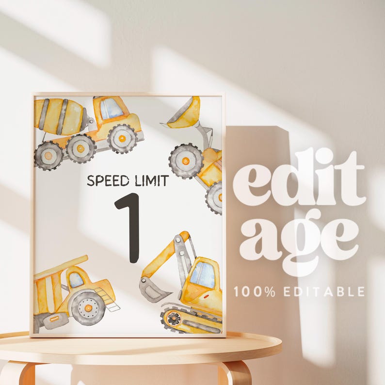 May include: A framed print featuring watercolor illustrations of construction vehicles in yellow and gray. The print includes the text "SPEED LIMIT 1". The background is white, and the frame is a light wood color.
