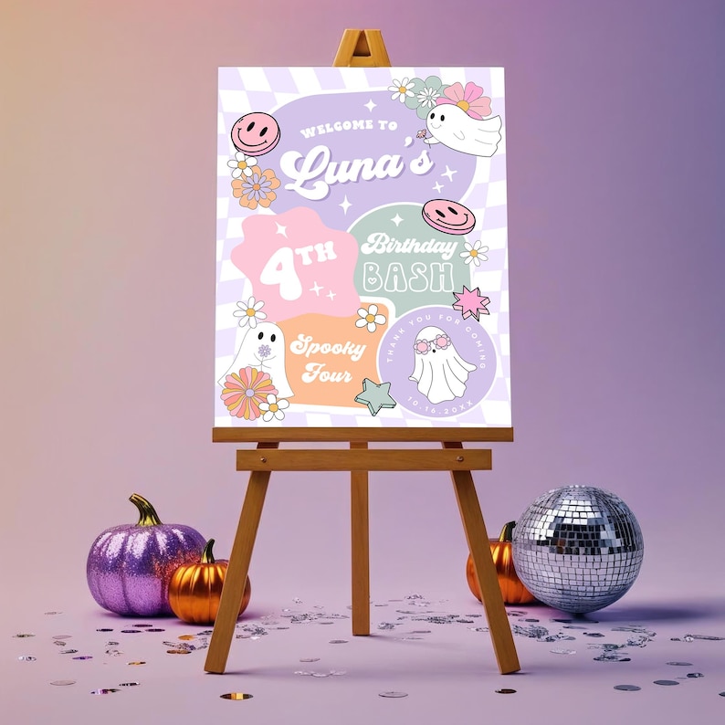 May include: A wooden easel displays a colorful birthday party sign with the text "Welcome to Luna's 4th Birthday Bash". The sign features ghost illustrations, flowers, and smiley faces. A purple glitter pumpkin, an orange pumpkin, and a disco ball are in front of the easel.