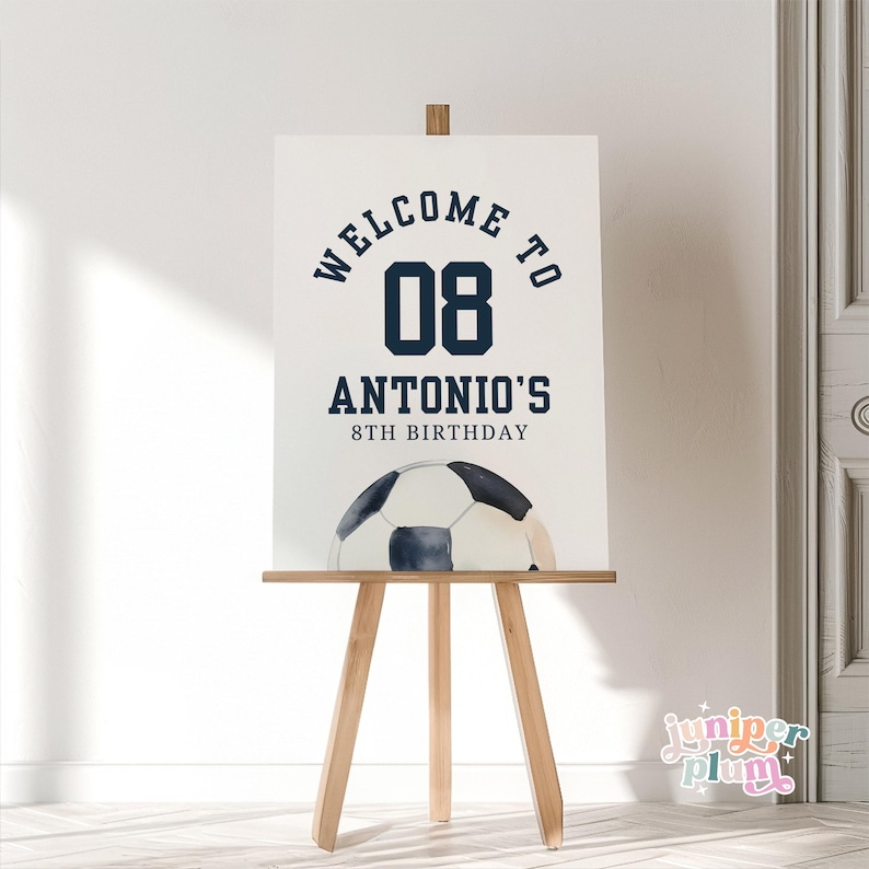 May include: Welcome to Antonio's 8th birthday party sign with a soccer ball graphic and the number 08 in navy blue.