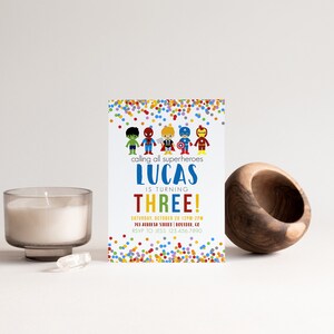May include: A colorful invitation with a confetti background. It says "calling all superheroes Lucas is turning THREE!" with a date and RSVP information.