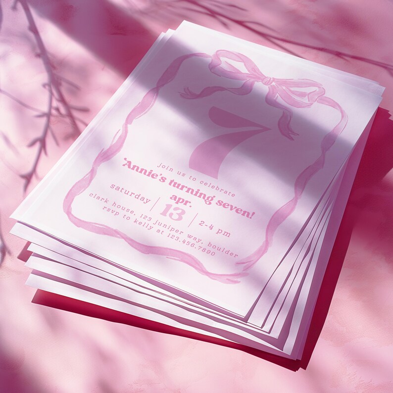 May include: A stack of pink invitations with a pink ribbon and bow design. The invitation reads 'Annie's turning seven!' with the date 'Saturday, April 13' and the time '2-4 pm'.