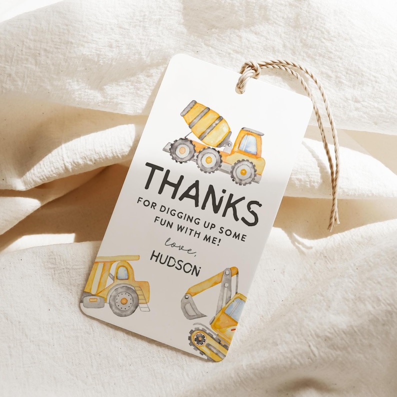 May include: A white gift tag with a watercolor illustration of construction vehicles, including a cement mixer, dump truck, and excavator. The tag reads "THANKS" and "FOR DIGGING UP SOME FUN WITH ME!" with the name "Hudson" below.