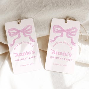 May include: Two rectangular gift tags with a light pink background. Each tag features a watercolor-style pink bow and the text "thank you for coming" above "Annie's BIRTHDAY PARTY" and the date "October 13, 20XX".