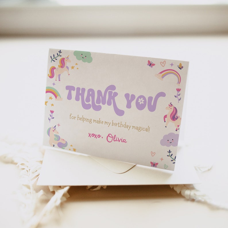 Puede incluir: Una tarjeta de agradecimiento con un dise&ntilde;o de unicornio, arco&iacute;ris y nubes en morado y rosa. El texto dice "THANK YOU for helping make my birthday magical! xoxo. Olivia."