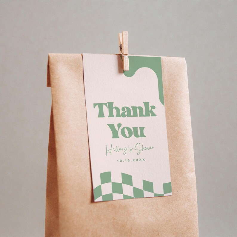 May include: A brown paper bag with a rectangular tag attached by a wooden clothespin. The tag features a light pink background, sage green wavy accents, a green checkered pattern, and the text Thank You, Hillary's Shower, and 10.16.20XX.