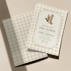 May include: Baby shower invitation with a beige gingham pattern. The invitation features a watercolor illustration of a duck in flight. The text reads "please join us for a BABY SHOWER" and includes event details.