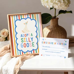 Puede incluir: Un letrero enmarcado con rayas verticales de arco&iacute;ris y un borde azul festoneado central que muestra un ganso con un sombrero de fiesta y el texto ADOPT A SILLY GOOSE, junto a un certificado de adopci&oacute;n de papel blanco con texto colorido.