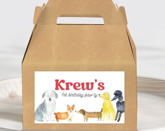 Puede incluir: Una caja de cartón marrón con asa. La caja tiene una etiqueta blanca con el texto "Krew's 1st birthday paw-ty" y una ilustración de acuarela de cinco perros.