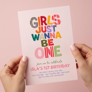 Może przedstawiać: Różowe zaproszenie urodzinowe z napisem "GIRLS JUST WANNA BE ONE" w kolorowych literach blokowych. Zaproszenie jest trzymane przez dwie ręce i zawiera szczegóły dotyczące 1. urodzin Isli.
