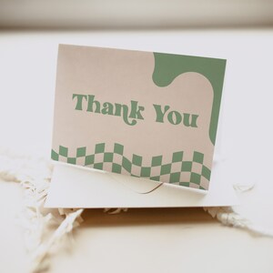 May include: A rectangular greeting card featuring the text Thank You in a dark green serif font. The card has a light beige background with a wavy dark green shape on the right side and a dark green and light beige checkered pattern at the bottom.