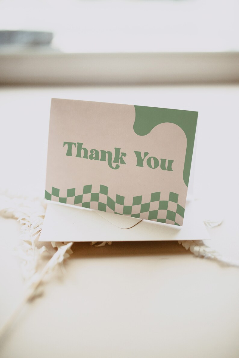 May include: A rectangular greeting card featuring the text Thank You in a dark green serif font. The card has a light beige background with a wavy dark green shape on the right side and a dark green and light beige checkered pattern at the bottom.