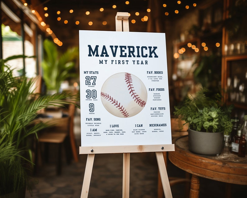 K&ouml;nnte beinhalten: Ein wei&szlig;es Schild mit dem Namen Maverick und dem Text "Mein erstes Jahr" in Blau. Das Schild zeigt eine Baseballgrafik und listet die Statistiken des Babys, seine Lieblingslieder, Lebensmittel, B&uuml;cher, Spielzeuge und Spitznamen auf.
