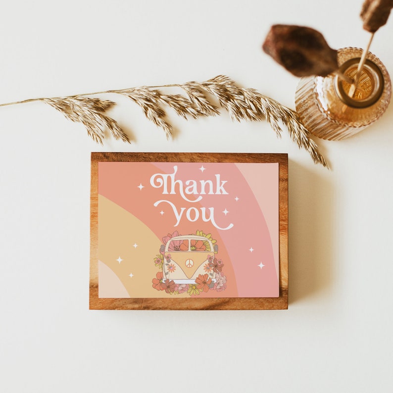 Puede incluir: Una tarjeta enmarcada en madera con fondo rosa y naranja. La tarjeta presenta una furgoneta vintage con flores y el texto "Gracias".