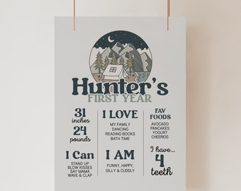 Könnte beinhalten: Ein hellgraues Poster mit dem Text "Hunter's FIRST YEAR" und einer Berg- und Zeltgrafik. Es listet Maße von 79 cm und 11 kg, Lieblingsspeisen und Dinge auf, die das Kind liebt und kann. Es steht auch "Ich habe... 4 Zähne."