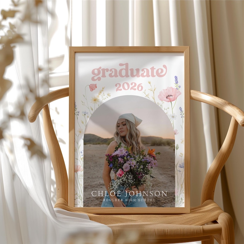 Puede incluir: Una foto de graduaci&oacute;n enmarcada con un marco marr&oacute;n claro. La foto muestra a una mujer sosteniendo flores, con las palabras "graduate 2026" en rosa arriba. El nombre "Chloe Johnson" y "Boulder High School" est&aacute;n debajo.