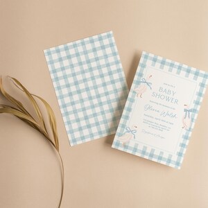 May include: A blue and white gingham baby shower invitation with a white border and pink and blue illustrations of swans with bows. The text on the invitation reads "Baby Shower" and "Jenna Walsh".