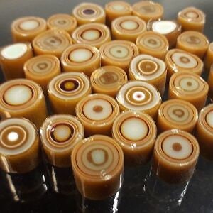 May include: A collection of brown and white glass beads with a swirling pattern. The beads are cylindrical and have a smooth, glossy finish.