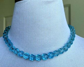 May include: A light blue glass bead necklace with faceted beads. The necklace is on a white mannequin.