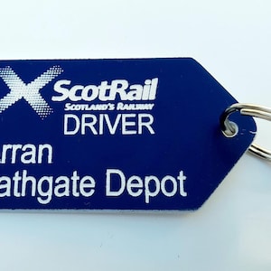 May include: A blue ScotRail Driver keyring with white text. The keyring features the ScotRail logo, the word "DRIVER", and the location "Arran Bathgate Depot". A silver key ring is attached.