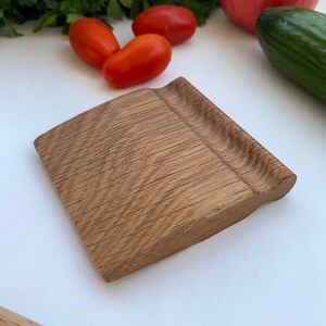 May include: A small, rectangular wooden pastry scraper with a slightly curved edge. The scraper is made of light brown wood with a natural grain pattern.