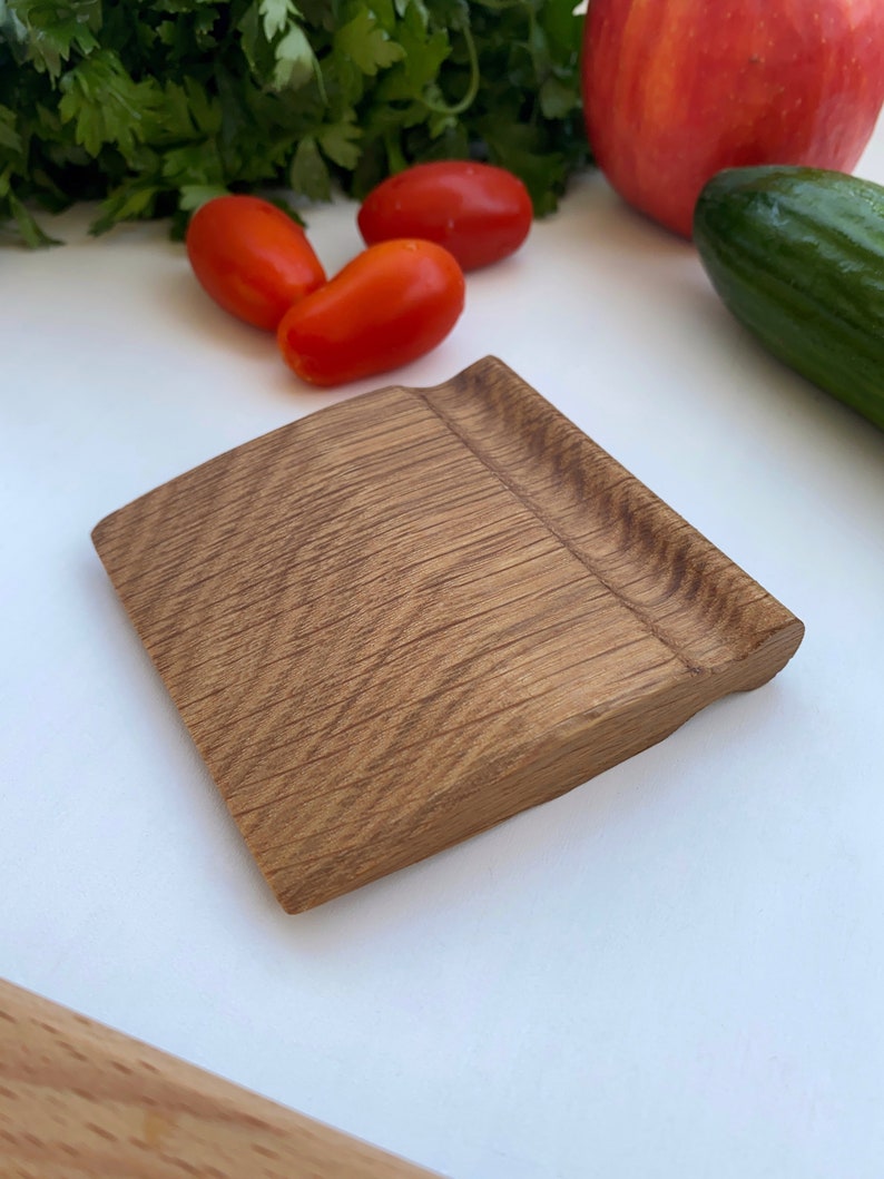 May include: A small, rectangular wooden pastry scraper with a slightly curved edge. The scraper is made of light brown wood with a natural grain pattern.