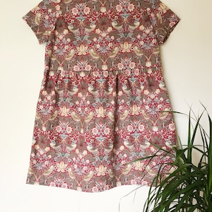 May include: A red, green, and white floral print dress with short sleeves and a gathered skirt.