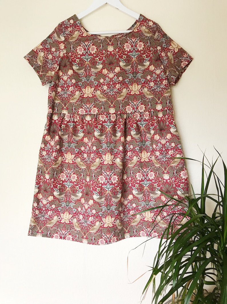 May include: A red, green, and white floral print dress with short sleeves and a gathered skirt.