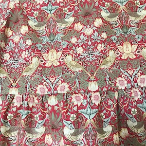 May include: Red fabric with a repeating pattern of stylized birds, flowers, and leaves. The pattern is in shades of green, gold, and white.