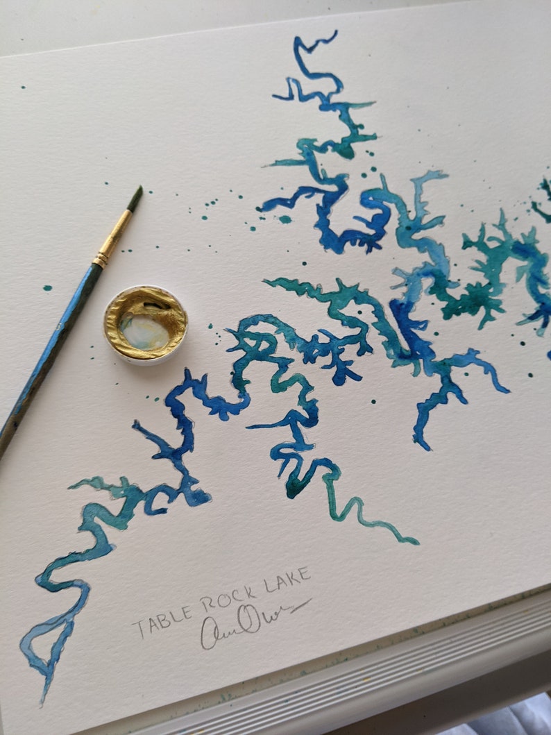 May include: A watercolor painting of Table Rock Lake, a popular destination in the Ozark Mountains. The painting is done in shades of blue and green, with a few splashes of white. The artist's signature, "Ann Oliver", is visible in the bottom right corner.
