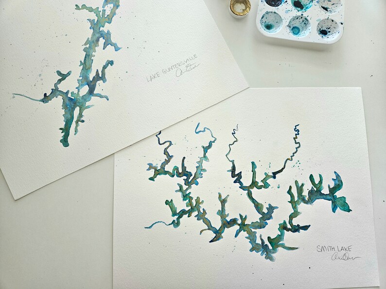 May include: Two watercolor paintings of lakes. The top painting is of Lake Guntersville, Alabama. The bottom painting is of Smith Lake, Alabama.