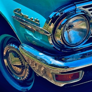 May include: A close-up of a vintage blue car with chrome accents. The car has a large, round headlight and a chrome bumper. The word "Comet" is visible on the side of the car.
