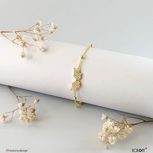 May include: A gold bracelet with a delicate chain and a sparkling butterfly charm. The charm is made of clear cubic zirconia stones.