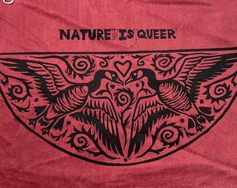 May include: A maroon fabric with the text "NATURE IS QUEER" printed in black. Below the text is a black graphic of two birds facing each other, with a heart between them. The birds are surrounded by decorative swirls and leaves.