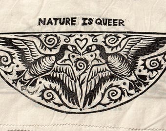 May include: A rectangular off-white fabric patch with pinked edges featuring a black block-print design. The text NATURE IS QUEER is printed above a symmetrical illustration of two geese with wings spread, facing each other with a heart between them.
