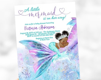 May include: A baby shower invitation featuring a watercolor illustration of a black mermaid. The invitation reads "A little mermaid is on her way!" in purple script. The mermaid has a teal tail and a pearl necklace.