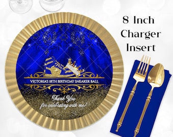 May include: Gold and blue 8 inch charger insert with a royal blue background and gold glitter. The insert features a pair of gold sneakers with a gold crown on top. The text "VICTORIA'S 18TH BIRTHDAY SNEAKER BALL" is written in gold lettering. The text "Thank You for celebrating with me!" is written in gold lettering.